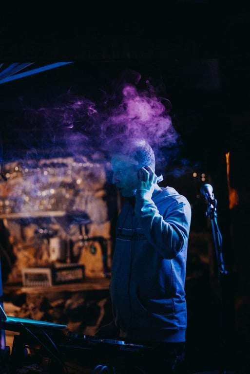 dj neno za pultom iz profila lijevom rukom drži slušalicu na uhu