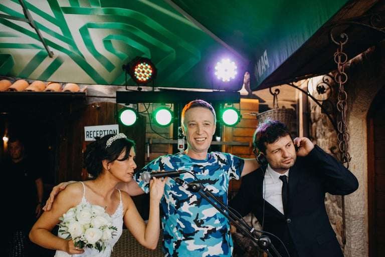 dj neno grli mladence za pultom, mladenac ima dj slušalice a mladenka mikrofon