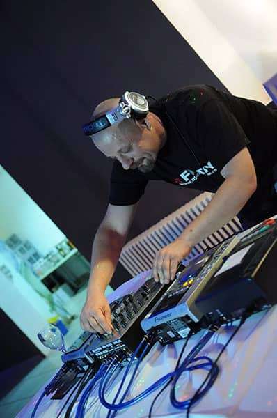 DJ Fredy za mix pultom s rasvjetom u pozadini, stvarajući nevjerojatnu atmosferu.